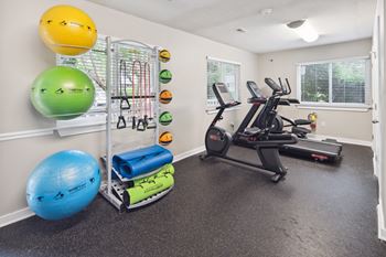 A home gym with a treadmill, exercise balls, and resistance bands.